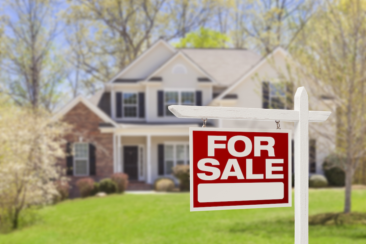 for sale sign in front of a large house